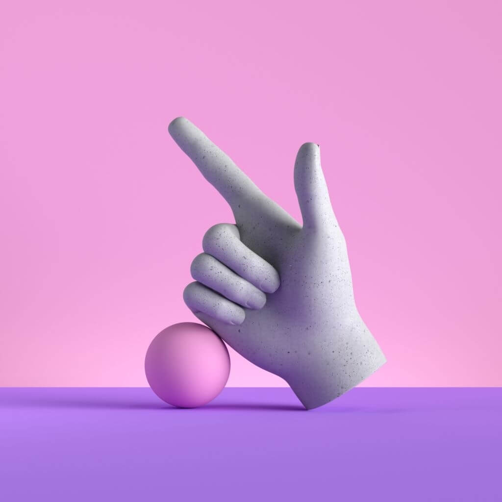 Stone hand pointing upwards resting on pink ball